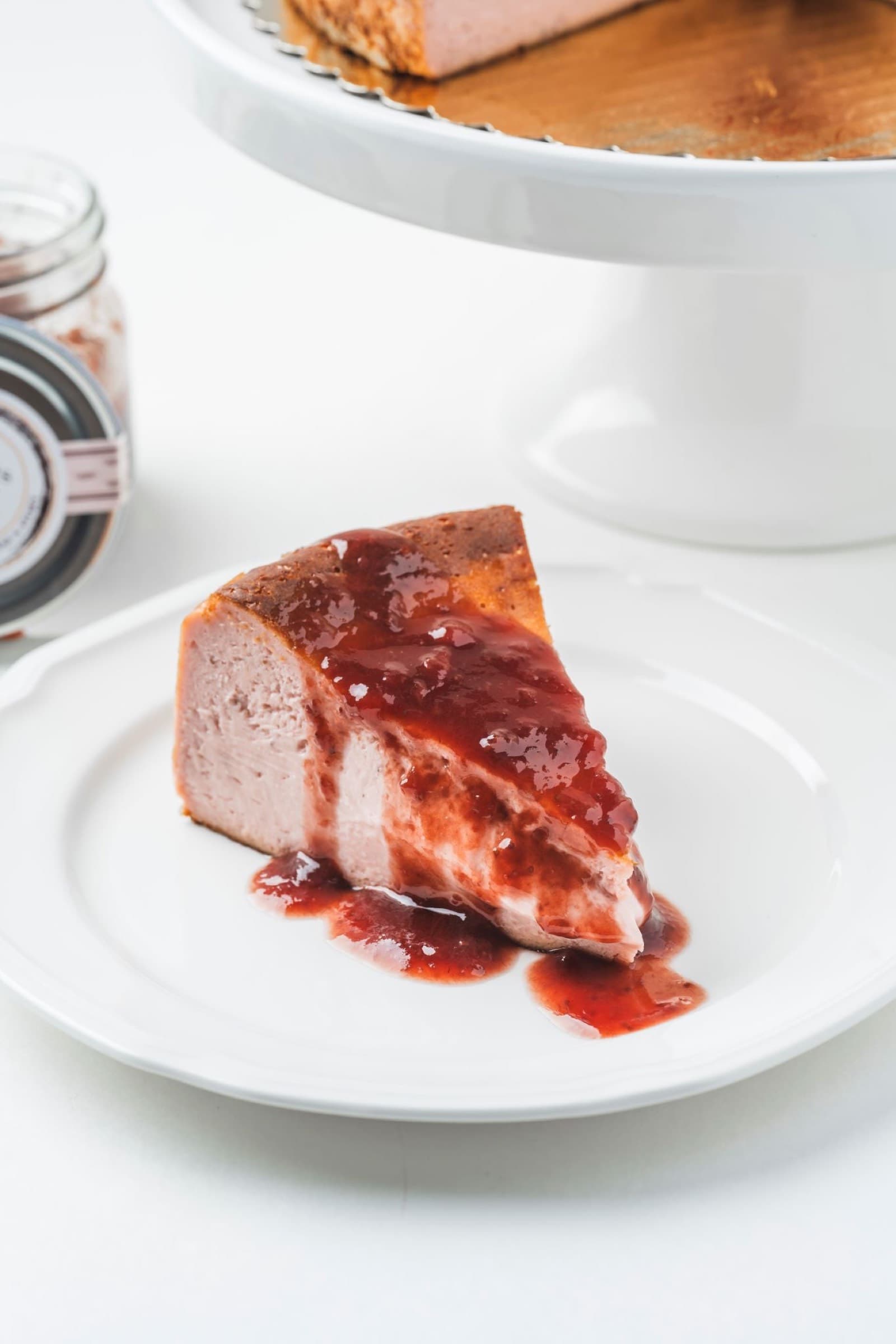 Strawberry balsamic Basque cheesecake slice plated with berry coulis on a white restaurant dessert plate